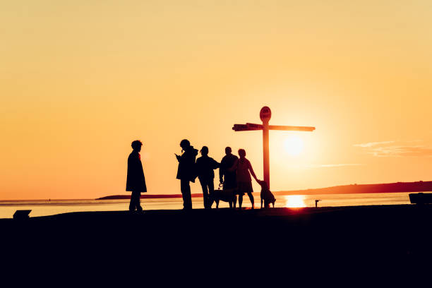 Two silhouettes of men talking at sunset or sunrise with dramatic sky and clouds.Dialogue and meeting two people on the horizon and skyline.Outlines of people in the sunlight.Golden hour with friends