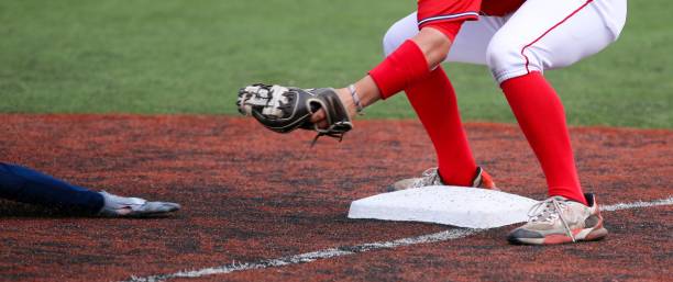 terzo baseman pronto a marcare il braccio di un corridore in scivolata durante una partita di baseball - high school baseball foto e immagini stock