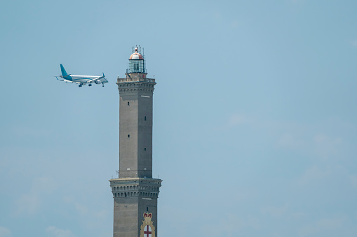 An airplane before landing near The Lanterna a lightouse in Genoa Italy Symbol in the sky background