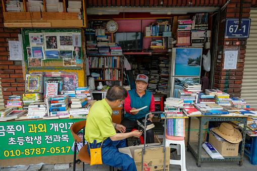 Busan, South Korea - May 26, 2023: Two men selling books on Bosu-dong Book Street, it is a famous book selling street in Busan, South Korea.