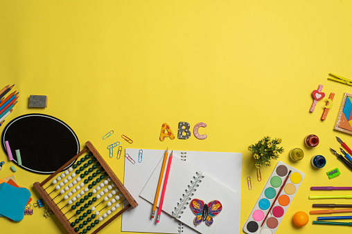 Education and learning tools and accessories for a back to school abstract image with on yellow background copy space flat lay top view on a pastel background
