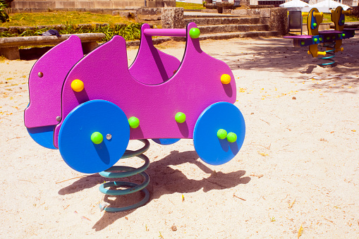 Seesaw in car shape, children outdoors playground toy.  Soft sand flooring. Galicia, Spain.