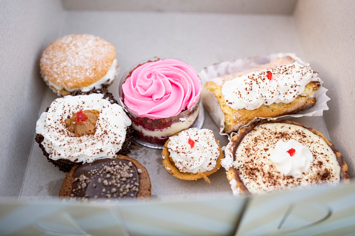 Variety of sweet frosted cupcakes in a box at a party