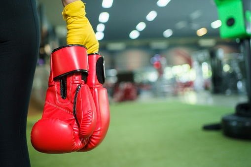Beautiful - confident Asian woman practicing boxing in the indoor boxing and fitness gym with female trainer, Asian female boxer resting or relaxing after practicing boxing.