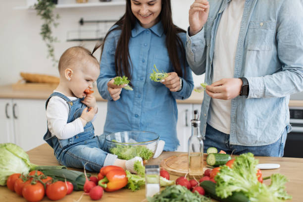 istock Mother smiling at baby eating tomato on breakfast table 1499178956