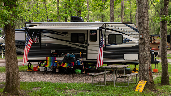 Rv motorhome parked in woods with American flag