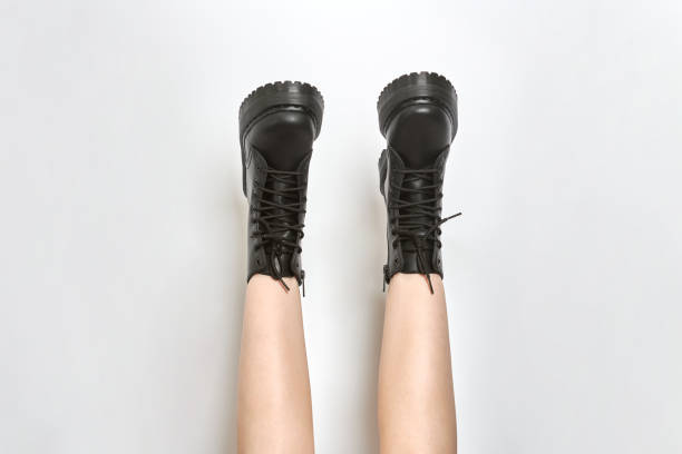 istock Woman legs in black combat boots on high heel platform with lug soles upside down, white background 1499179372