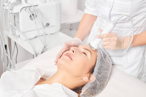Beautician makes ultrasound skin tightening for rejuvenation woman face using phonophoresis stock photo
