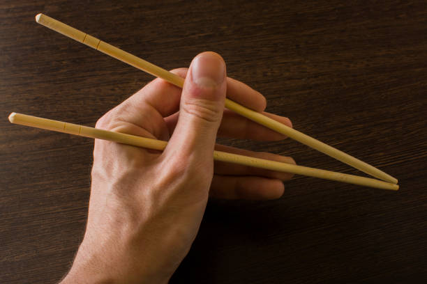 istock The left hand of a man using bamboo chopsticks on a wooden background 1499182148