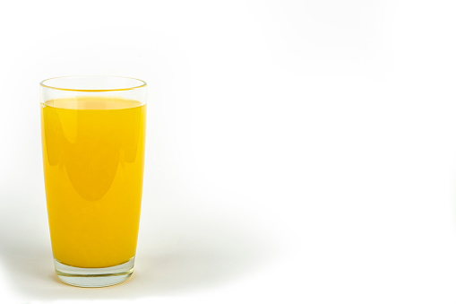 Orange juice yellow-orange in glass isolated on white