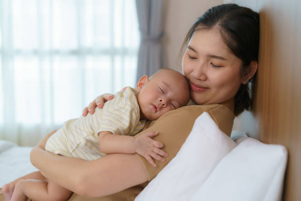 The Asian mother hugged her young son so that she could have a good sleep in the bedroom at home, Represents love and family stock photo