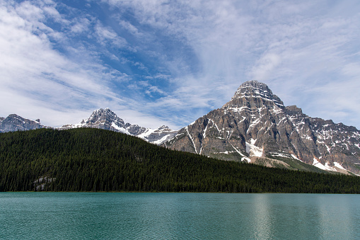 View over Waterfowl Lakes, Alberta, Canada with in background the snow covered mountain White Pyramid in the Canadian Rockies of Banff National Park against a white clouded blue sky