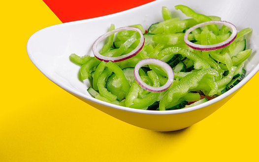 A plate of thin sliced cucumbers and green bell peppers
