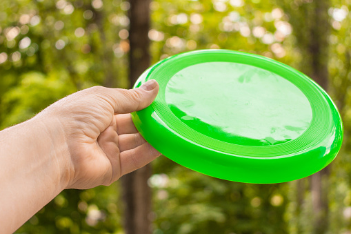 The hand with the disc to play frisbee on the background of summer blue sky. Concept of outdoor games.