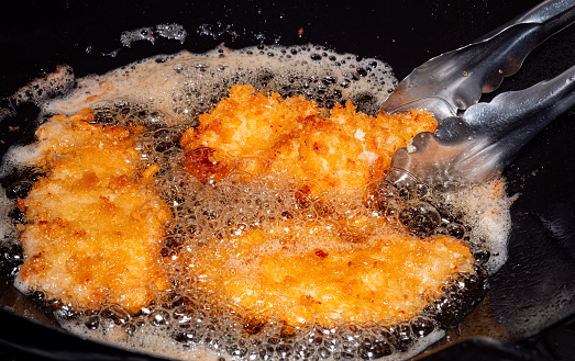 Breaded Fried Chicken. Foods fried in boiling oil in a Chinese wok. Cooking by frying in hot oil. Bubbles appear from frying