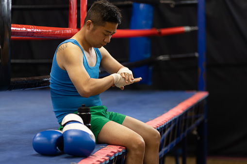 Young Chinese man going for boxing training. In this photo he is doing his preparation or taking a break.
