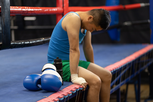 Young Chinese man going for boxing training. In this photo he is doing his preparation or taking a break.