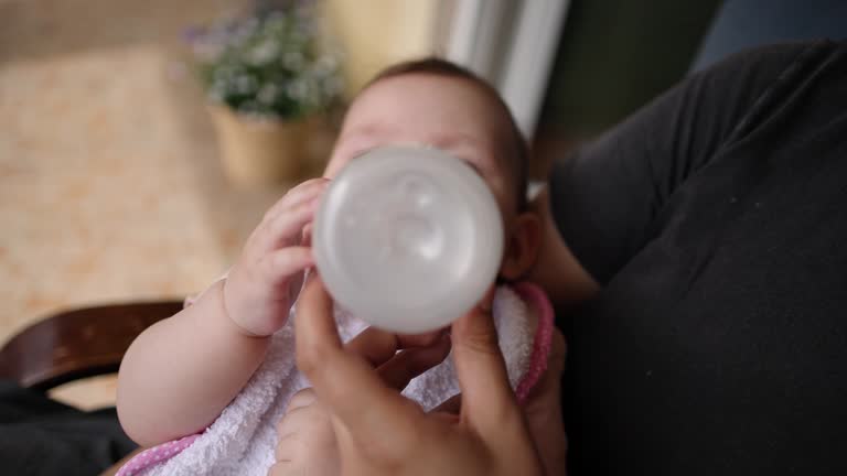 B-roll of mother feeding her baby girl with a milk in the baby cup