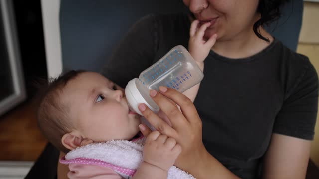 B-roll of mother feeding her baby girl with a milk in the baby cup
