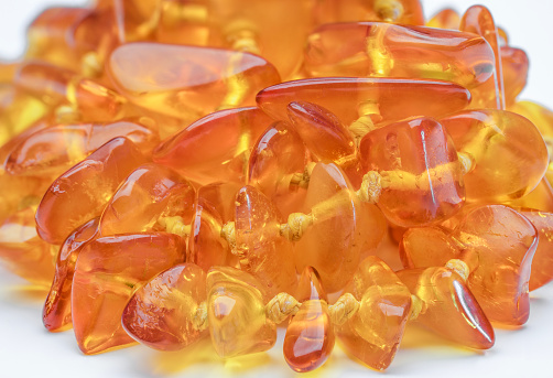 Macro of amber necklaces wrapped in a circle on a white background