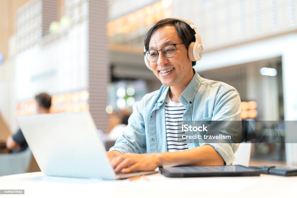 Smart confidence asian startup entrepreneur business owner businessman smile using laptop working online while listening music wireless headphone working relax leisure in cafe Laptop Stock Photo