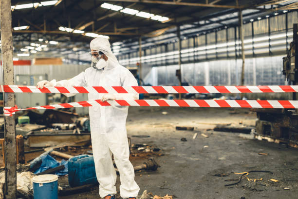 Worker in PPE safety suit with area closed barricade security tape in danger dirty area from virus infected chemical leak Worker in PPE safety suit with area closed barricade security tape in danger dirty area from virus infected chemical leak biohazard cleanup stock pictures, royalty-free photos & images