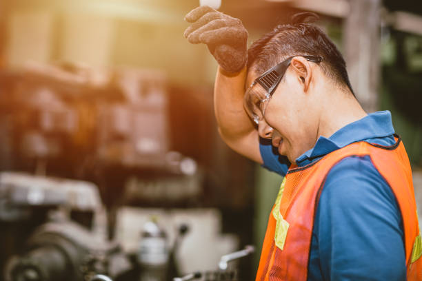 Tired fatigue exhausted engineer feel sick worker from hard working in factory sweat hot bad airflow workplace. stock photo