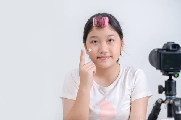 Asian girl applying foundation on cheek and recording video on modern camera Beautiful and charming girl and successful beauty blogger making education lessons with makeup tutorials. Asian girl applying foundation on cheek and recording video on modern camera free girl download stock pictures, royalty-free photos & images