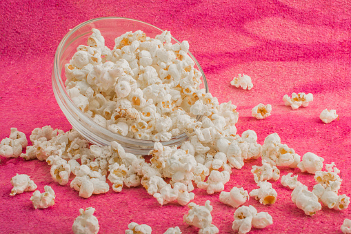 popcorn in a glass plate, on a pink uneven background