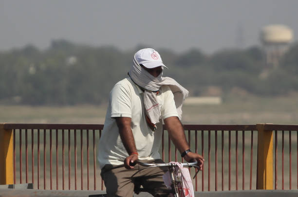 An cyclist during the heatwave conditions  at the bank of river  Gnages in Prayagraj, India.