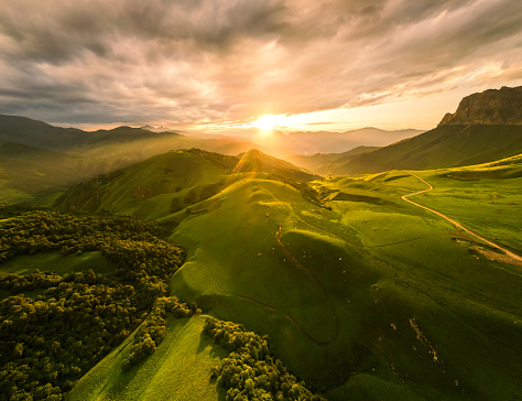 Aerial view of the green mountains and hills at sunset. Summer landscape. Aktoprak Pass in North Caucasus, Russia.