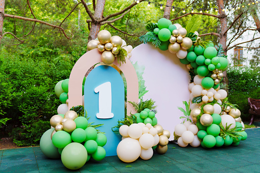 Photo zone in the park at a children's birthday party - green balloons form an arch with the number 1. This bright and cheerful decoration creates a magical atmosphere.