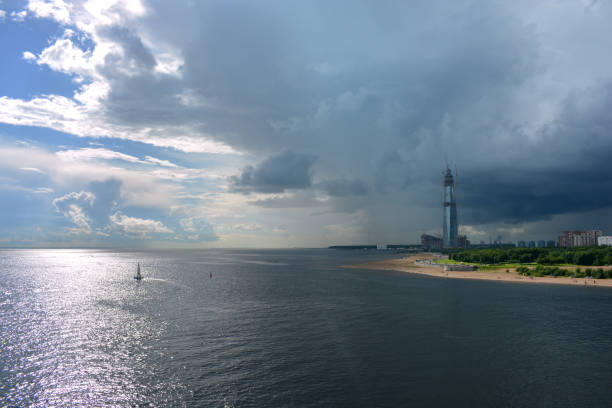 A skyscraper, under construction on the seashore under the sky changing from blue to a thunderstorm in St.Peterburg.