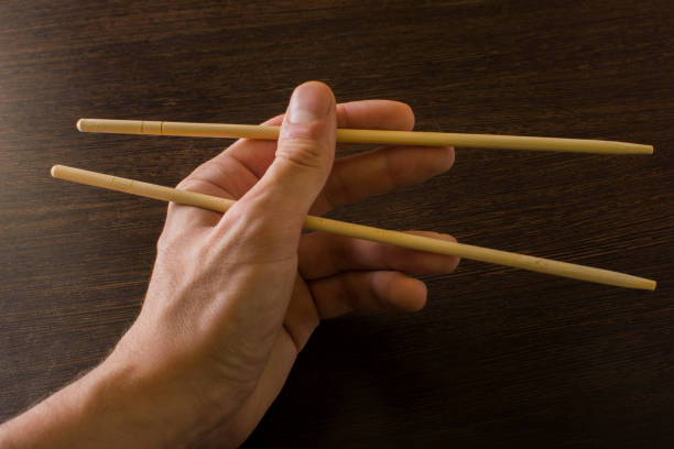 istock The left hand of a man using bamboo chopsticks on a wooden background 1499226181