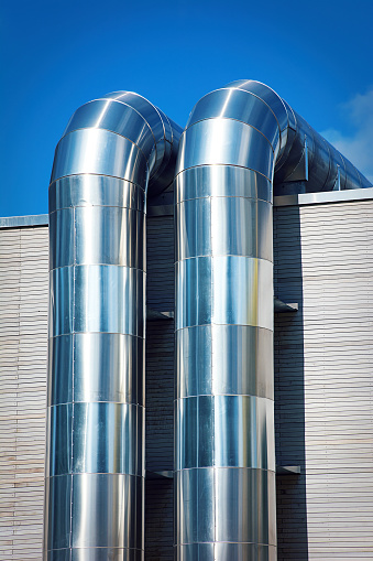 Two Pipes made of stainless steel for heat conduction on the house wall of a modern building.