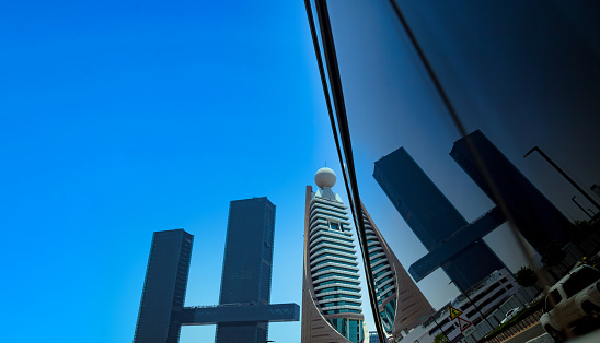Modern skyscrapers of Dubai sunny day with reflection, cityscape abstract background. Urban landscape of new city towers at blue sky. Construction and modern architecture concept. Copy ad text space