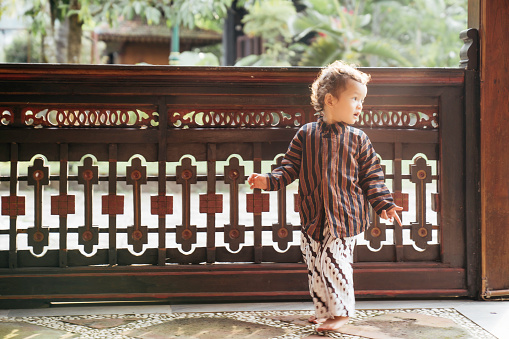 young kid using surjan (Yogyakarta tradition dress) playing at the joglo house