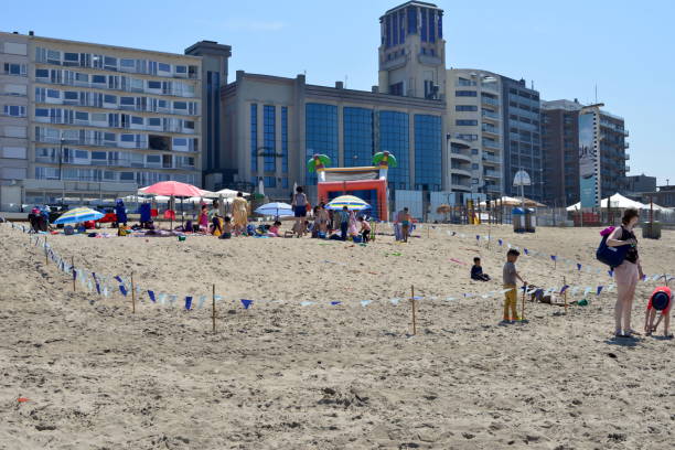 Blankenberge, West-Flanders, Belgium - June 11, 2023: kindergarten teachers have marked off a domain for the children on the sand beach with wooden sticks and pennants hanging from a thread