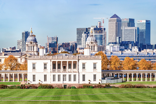 London, UK - October 25, 2015: Autumn day view to Queen's House and the Naval College and with the Canary Wharf skyline with its corporate office buildings in the background.