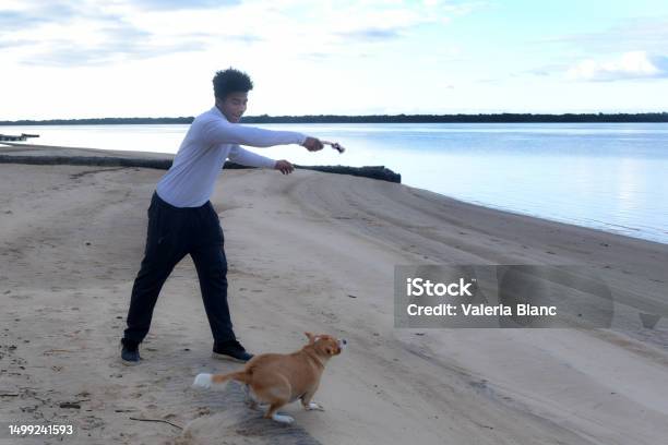 Young Man With Pet On The River Bank Stock Photo - Download Image Now - 20-24 Years, Adult, Adults Only