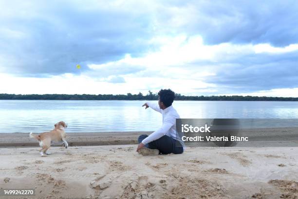 Young Man With Pet On The River Bank Stock Photo - Download Image Now - 20-24 Years, Adult, Adults Only