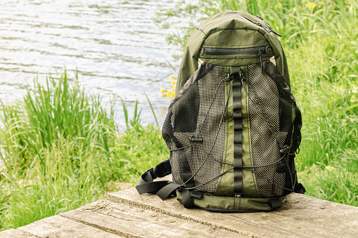 Travel backpack standing on the background of beautiful pond and nature view. Active lifestyle, freedom and travel concept