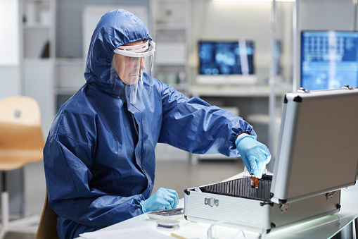 Side view portrait of male scientist wearing protective suit working with hazardous materials in laboratory, copy space