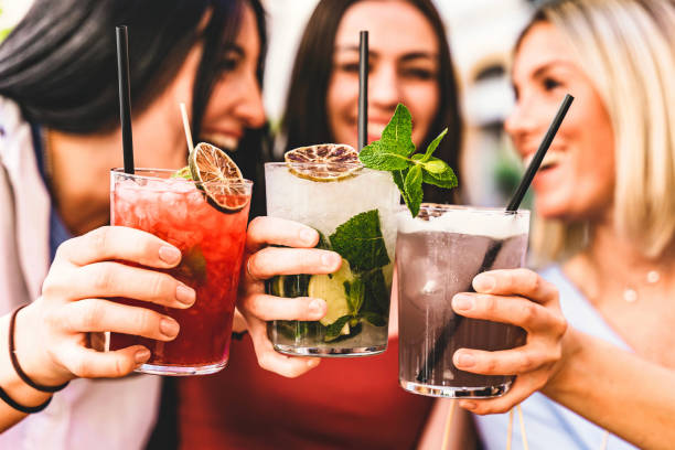 grupo de amigos felizes brindando e bebendo coquetéis extravagantes no terraço do bar - três meninas jovens bebem mojito e copo piscando juntos no pub desfrutando de happy hour na festa de verão - conceito life style - coral break - fotografias e filmes do acervo