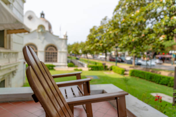 Stylish outdoor seating area featuring woven rattan furniture with bright orange cushions, surrounded by lush greenery for a relaxing patio vibe.