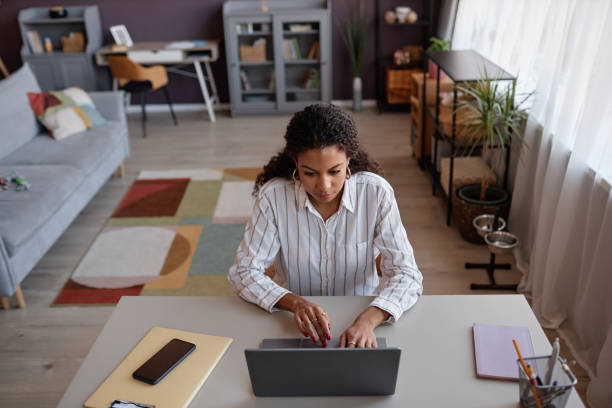 istock Black young woman using laptop working at home office in cozy setting 1499252744