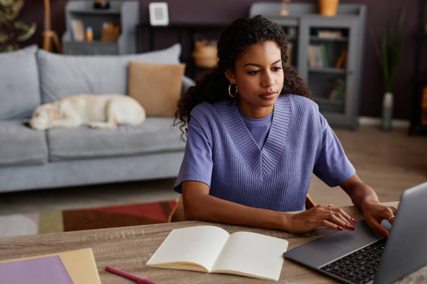 istock Black young woman working from home and using laptop with dog 1499252805