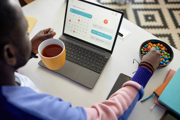 istock Black man enjoying candy snack and coffee while using laptop at desk 1499256646