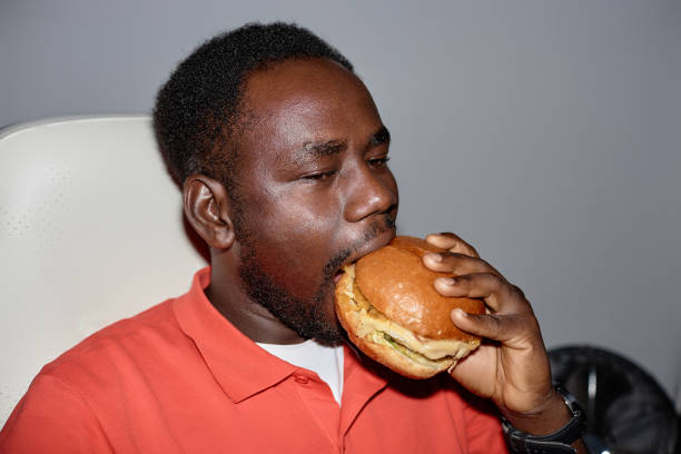 istock Minimal side view black man eating burger indoors 1499256711