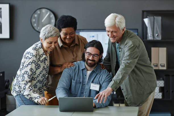 istock Diverse group of smiling senior people using laptop with man in computer class 1499258473